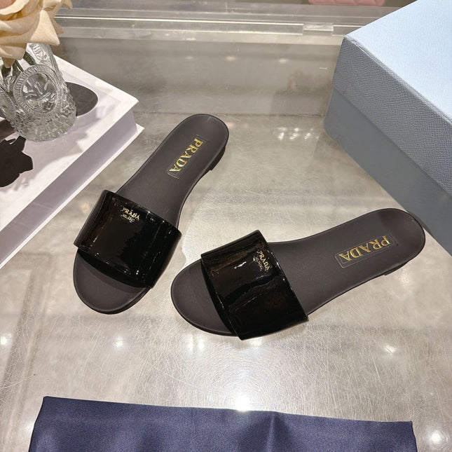 PRADA 26S LOGO EMBOSSED SLIDE SANDALS IN BLACK PATENT CALFSKIN