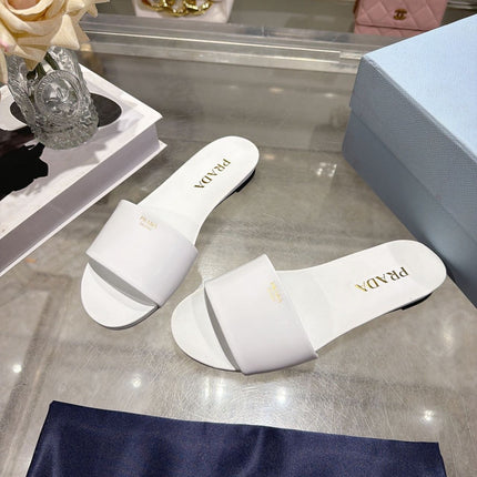 PRADA 26S LOGO EMBOSSED SLIDE SANDALS IN WHITE PATENT CALFSKIN
