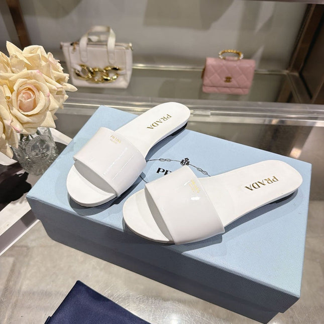PRADA 26S LOGO EMBOSSED SLIDE SANDALS IN WHITE PATENT CALFSKIN