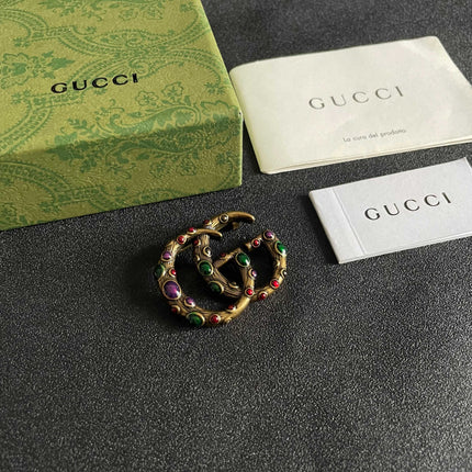 GUCCI 26S INTERLOCKING G MULTICOLOR GEM LOGO BROOCH IN ANTIQUE GOLD TONE METAL 625634